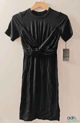 black leather dress hanging on a hanger on a wall