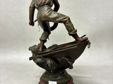 bronze statue of a man standing on a boat with a dog