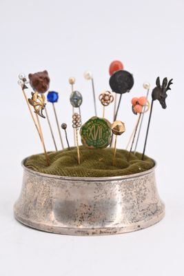 a small silver bowl with pins and pins in it