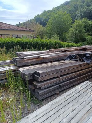 un tas de bois posé sur le sol à côté d'un bâtiment