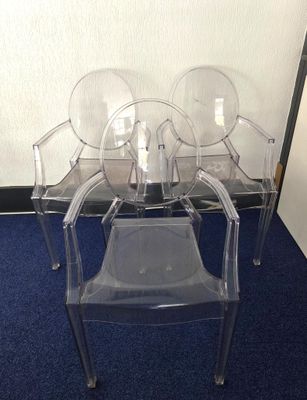 trois chaises transparentes posées sur un sol recouvert de moquette bleue