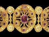un gros plan sur un bracelet en or orné de pierres violettes