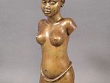 statue of a woman with a large breast on a wooden base