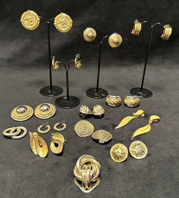 a group of gold earrings and brooches on stands