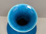 a small blue vase sitting on a white table