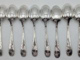 six silver spoons are lined up in a row on a table