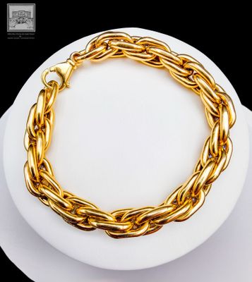gold plated chain bracelet on a white plate on a black background