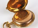 an image of a gold pocket watch sitting on a white surface