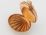 a gold locke with a shell inside on a white surface