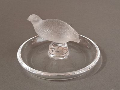 a glass bird sitting on top of a glass plate