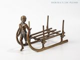 une figurine en bronze représentant un garçon sur une luge