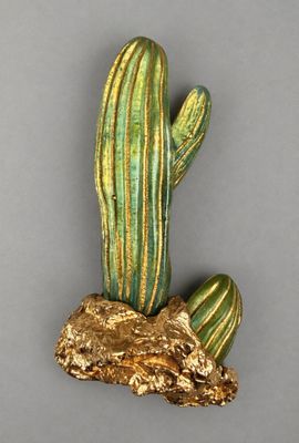 gold and green cactus figurine sitting on top of a piece of wood