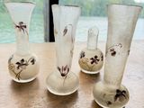 cinq vases en verre posés sur une table près d'une fenêtre