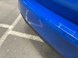 a blue car parked in a parking lot with its door open