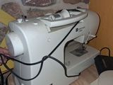une machine à coudre blanche posée sur une table près d'un mur de briques
