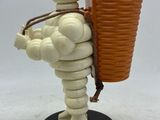 the figurine is holding a cup and a basket on a stand