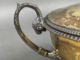 a silver and gold bowl with a handle on a table