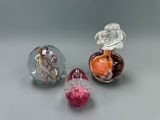 trois objets en verre de couleurs différentes posés sur une table