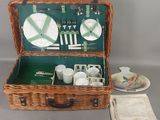 un panier de pique-nique en osier contenant des assiettes, des tasses et des soucoupes