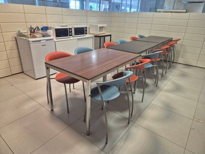 tables and chairs in a room with a microwave and microwave oven