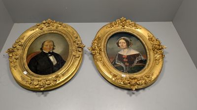 Deux portraits encadrés, représentant un homme et une femme, sont exposés