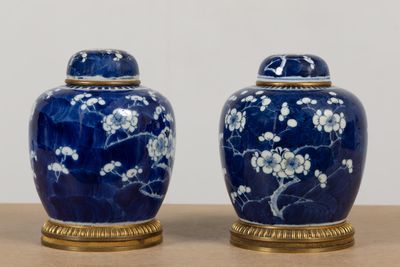 two blue vases with white flowers on them sitting on a table