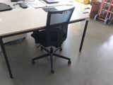 un bureau blanc avec une chaise noire et un ordinateur portable posé dessus