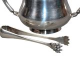 a silver tea pot and two spoons on a white background
