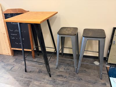 three stools and a table in a room with a chalk board