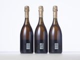three bottles of champagne sitting on top of a white table