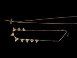 two gold necklaces with triangles on them on a black background