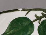 a white plate with green leaves on it on a table