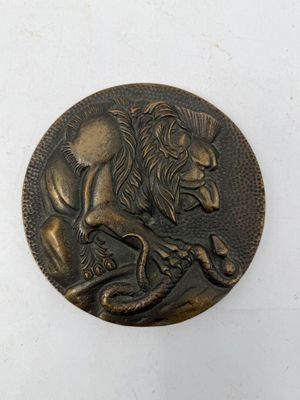 une image d'une pièce de bronze sur laquelle figure un lion couché sur le dos