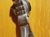 someone is holding a watch on their wrist on a wooden surface