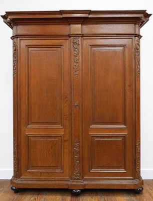 a large wooden armoire with two doors and a carved top