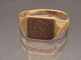 a gold signet ring with a monogram on it