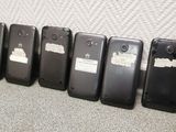 four cell phones are lined up against a wall in a row
