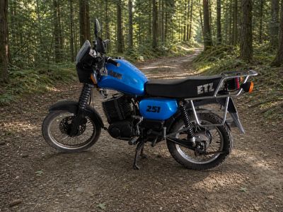 une moto bleue garée sur un chemin de terre dans les bois