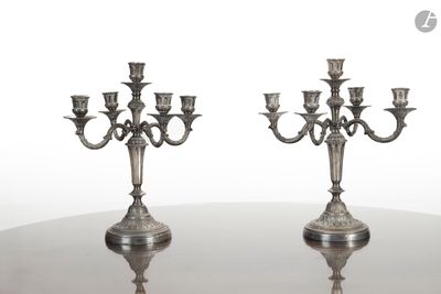 paire de candélabres anciens en métal argenté posés sur une table en verre