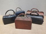 three small leather suitcases are lined up on a table