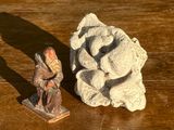 une petite statue représentant un homme assis près d'un rocher