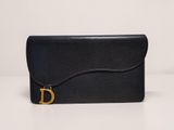 a black leather clutch bag with a gold buckle on the front