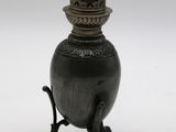 un vase noir posé sur un socle, sur une surface blanche