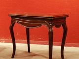 une petite table en bois avec un mur rouge en arrière-plan