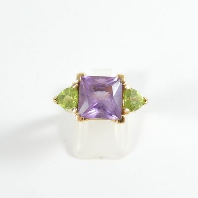 a close up of a ring with an amethorate and peridot stones