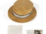 a straw hat with a striped band and a handwritten note