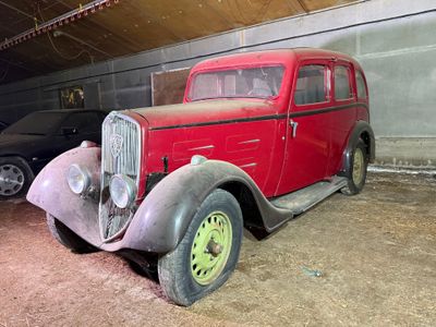 une vieille voiture rouge garée dans un garage à côté d'une voiture noire