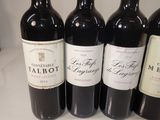 several bottles of red wine are lined up on a counter