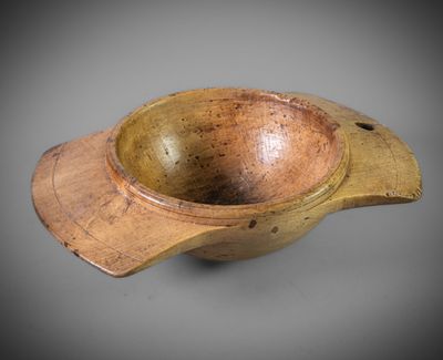 an old wooden bowl with a wooden handle on a gray surface