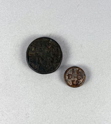 une vieille pièce posée à côté d'une pièce plus petite sur une surface blanche